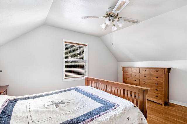 bedroom featuring vaulted ceiling, a textured ceiling, light wood-type flooring, and ceiling fan