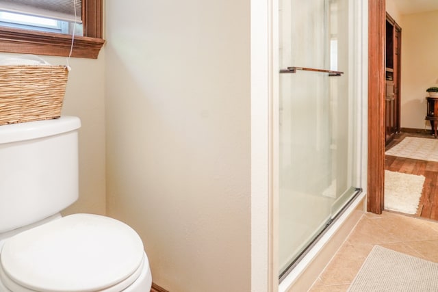 bathroom with toilet, a shower with shower door, and hardwood / wood-style floors