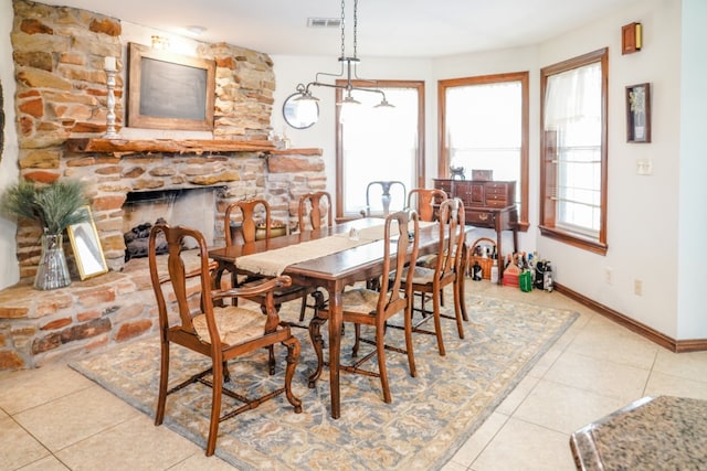 dining room featuring light tile patterned flooring and a stone fireplace