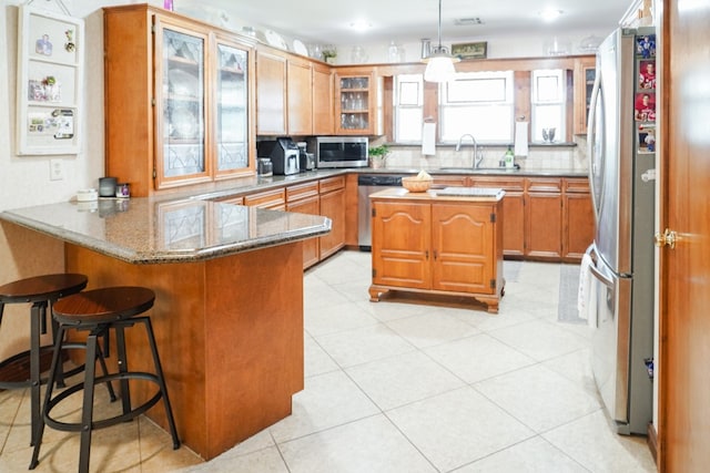 kitchen featuring decorative backsplash, a breakfast bar area, kitchen peninsula, sink, and appliances with stainless steel finishes