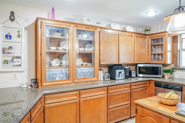 kitchen featuring light stone counters, stainless steel appliances, decorative backsplash, and hanging light fixtures