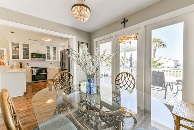 dining space with light hardwood / wood-style floors and an inviting chandelier