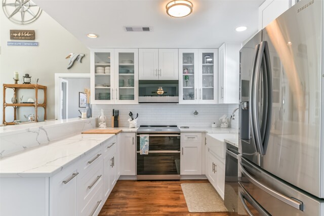 kitchen featuring light stone counters, dark hardwood / wood-style flooring, decorative light fixtures, white cabinets, and appliances with stainless steel finishes