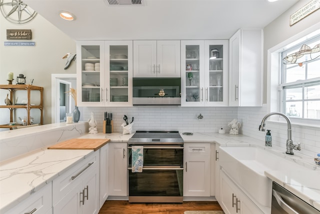 kitchen with white cabinets, light stone countertops, stainless steel appliances, and light hardwood / wood-style flooring