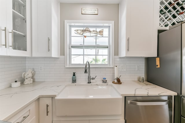 kitchen with backsplash, sink, white cabinets, and stainless steel dishwasher