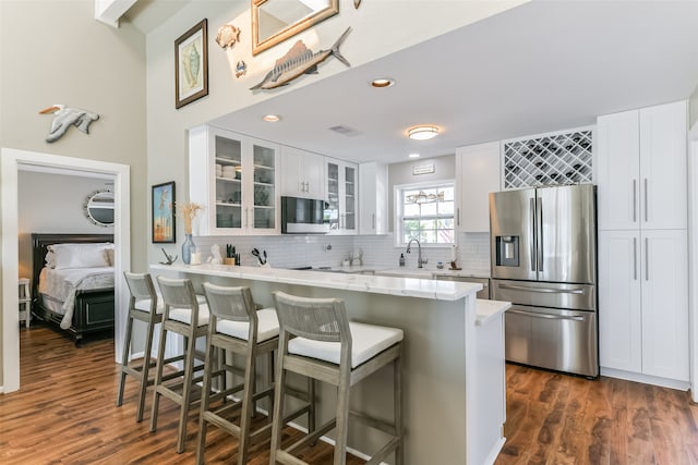 kitchen with dark hardwood / wood-style flooring, white cabinetry, a breakfast bar area, and appliances with stainless steel finishes