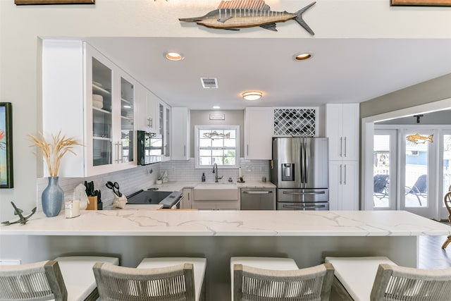 kitchen featuring a kitchen bar, kitchen peninsula, white cabinetry, and black appliances