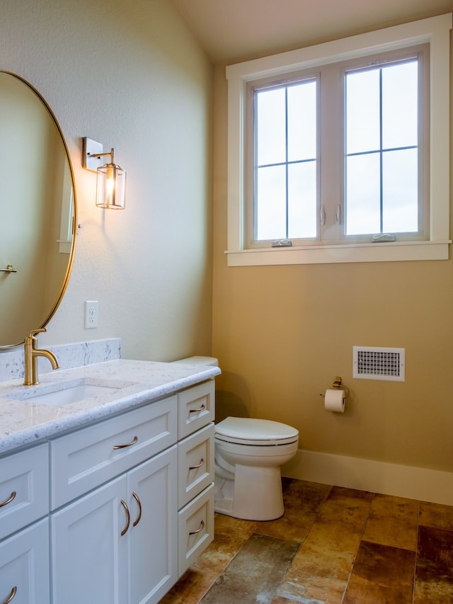 bathroom featuring vanity, toilet, and plenty of natural light