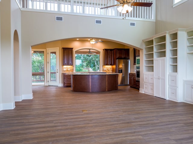 kitchen featuring backsplash, appliances with stainless steel finishes, a high ceiling, and dark hardwood / wood-style floors