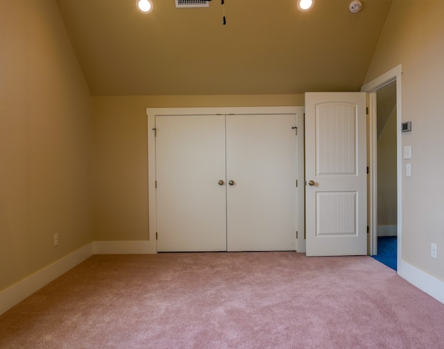 unfurnished bedroom featuring vaulted ceiling, light colored carpet, and a closet