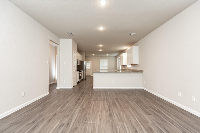 unfurnished living room with hardwood / wood-style floors and a textured ceiling