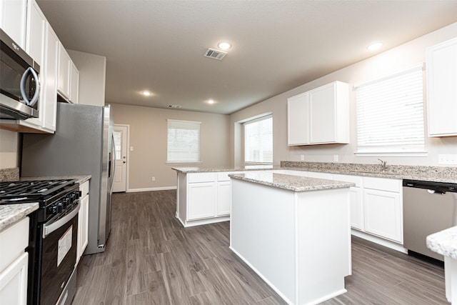 kitchen featuring appliances with stainless steel finishes, a center island, white cabinetry, and light stone counters