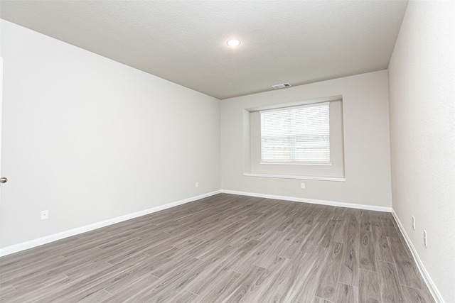 unfurnished room with hardwood / wood-style flooring and a textured ceiling