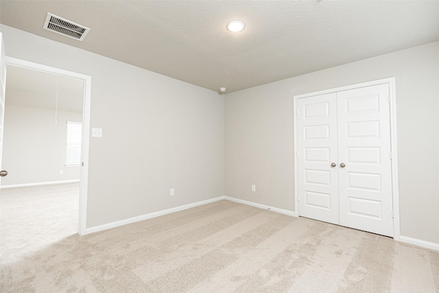 empty room featuring light carpet and a textured ceiling