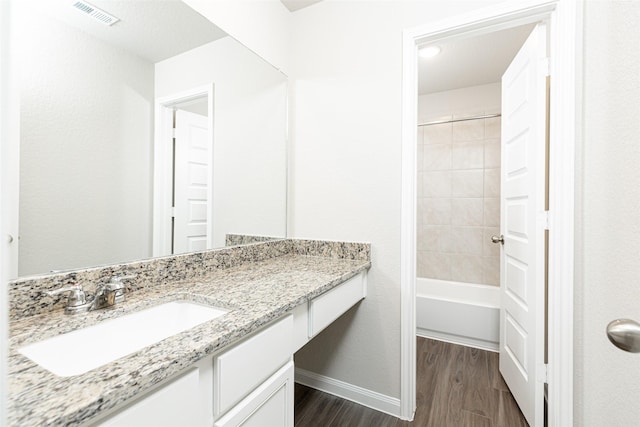 bathroom with vanity, wood-type flooring, and tiled shower / bath combo