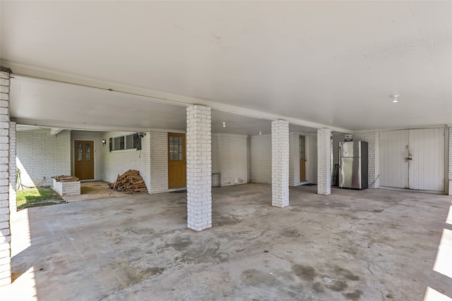 basement featuring brick wall and stainless steel fridge