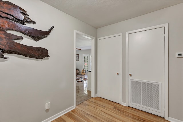 hallway with a textured ceiling and light wood-type flooring