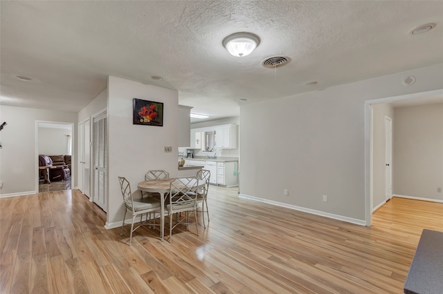 dining room with light hardwood / wood-style floors and a textured ceiling