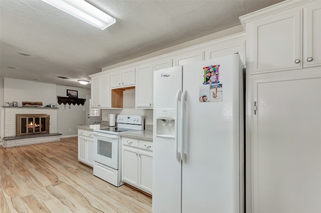 kitchen with white appliances, a textured ceiling, a brick fireplace, white cabinetry, and light hardwood / wood-style floors