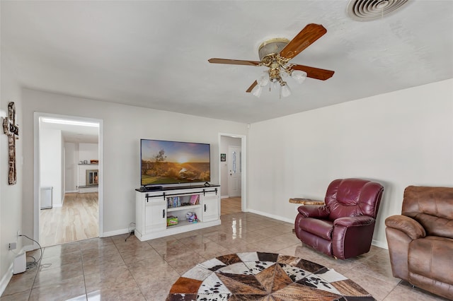 living room with a fireplace and ceiling fan