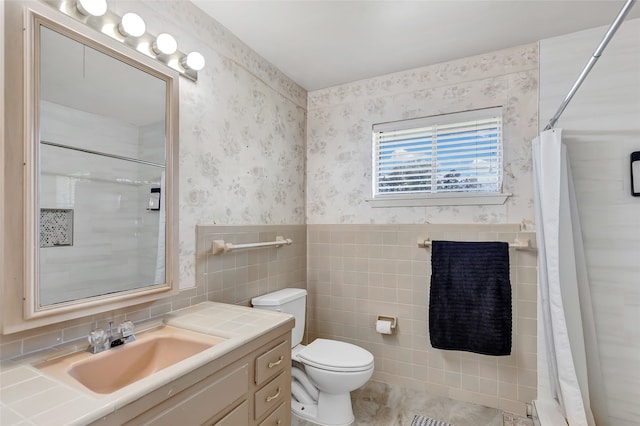 bathroom with tile walls, vanity, toilet, and walk in shower