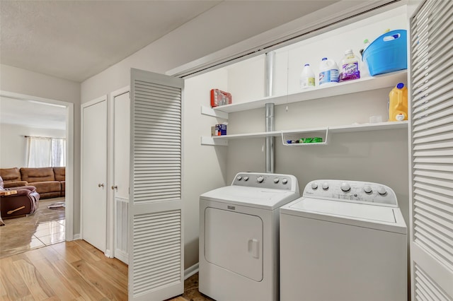 clothes washing area with light hardwood / wood-style floors and separate washer and dryer