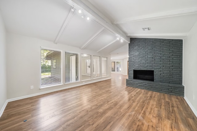 unfurnished living room featuring vaulted ceiling with beams, hardwood / wood-style floors, track lighting, and a fireplace