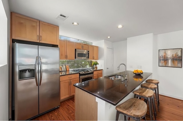 kitchen featuring hardwood / wood-style flooring, a breakfast bar, sink, and stainless steel appliances