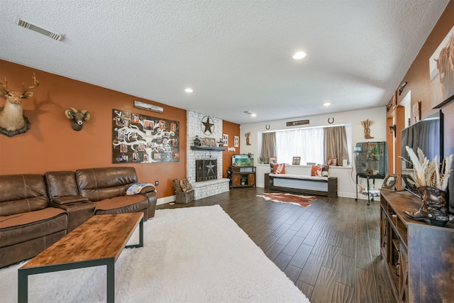 living room featuring a stone fireplace, a textured ceiling, and dark hardwood / wood-style flooring