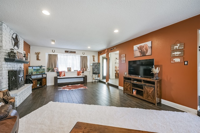 living room featuring a textured ceiling, a brick fireplace, and dark hardwood / wood-style floors