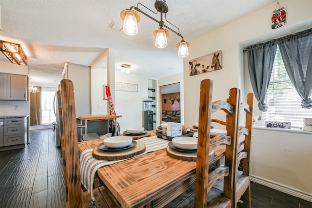 dining area featuring a textured ceiling, dark hardwood / wood-style floors, and a healthy amount of sunlight