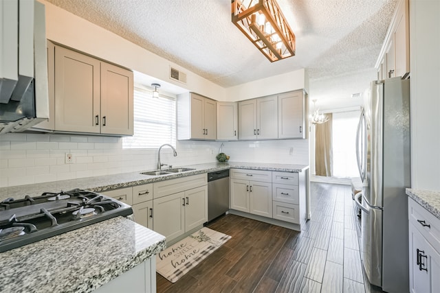 kitchen featuring dark hardwood / wood-style floors, backsplash, sink, appliances with stainless steel finishes, and a textured ceiling