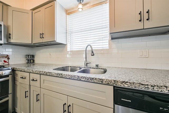 kitchen featuring cream cabinets, backsplash, appliances with stainless steel finishes, light stone countertops, and sink