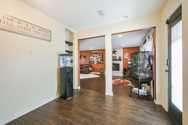 interior space with decorative columns, a textured ceiling, dark hardwood / wood-style flooring, and built in shelves