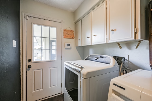 washroom with cabinets, a textured ceiling, washing machine and dryer, and dark hardwood / wood-style floors