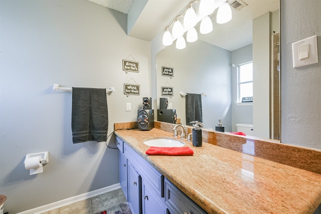 bathroom with toilet, a textured ceiling, and vanity