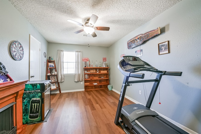 exercise area with ceiling fan, a textured ceiling, and light hardwood / wood-style flooring