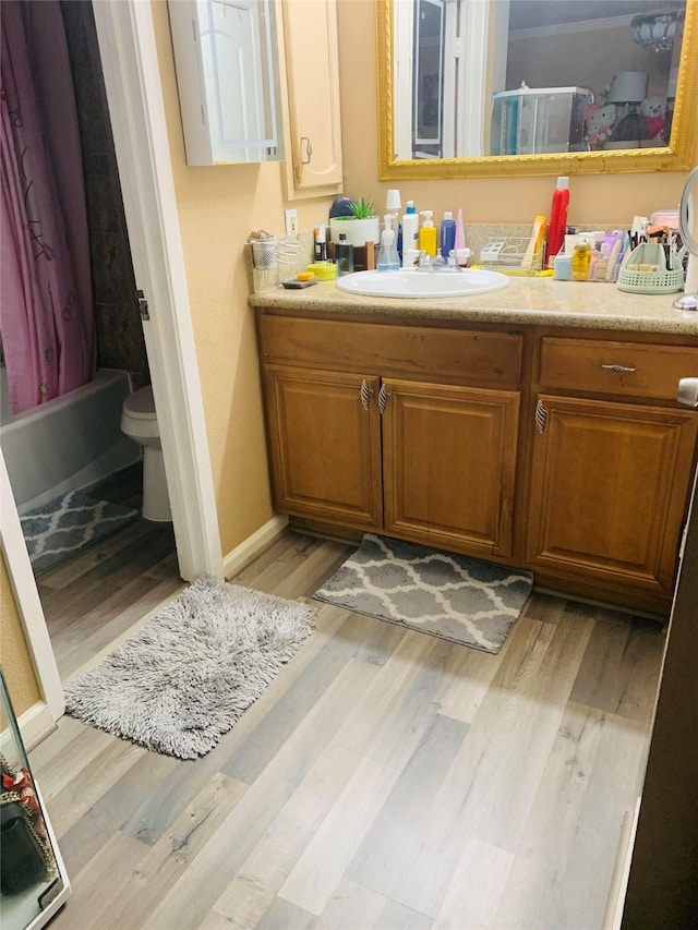 full bathroom with vanity, toilet, wood-type flooring, and shower / tub combo