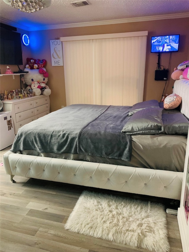 bedroom with ornamental molding, a textured ceiling, and hardwood / wood-style floors