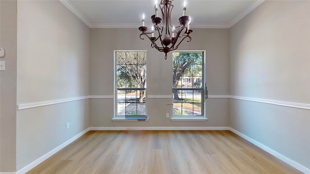 spare room featuring a chandelier, crown molding, light hardwood / wood-style flooring, and plenty of natural light