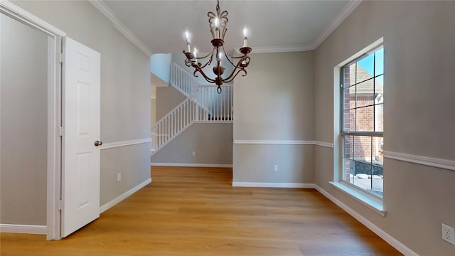 unfurnished dining area with ornamental molding, a chandelier, and light wood-type flooring