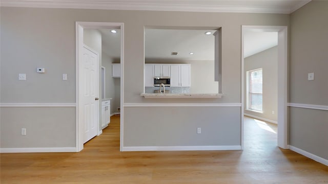 kitchen with light hardwood / wood-style flooring, sink, light stone countertops, crown molding, and white cabinetry