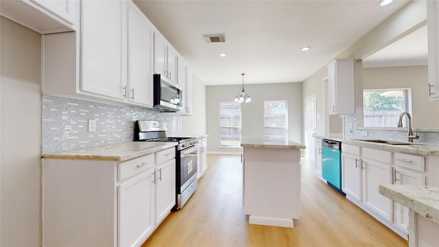 kitchen with white cabinetry, decorative light fixtures, stainless steel appliances, and light hardwood / wood-style floors