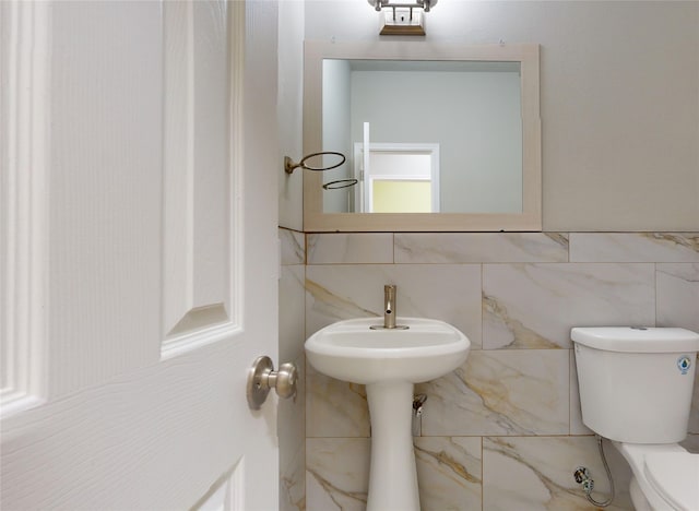 bathroom featuring toilet and tile walls