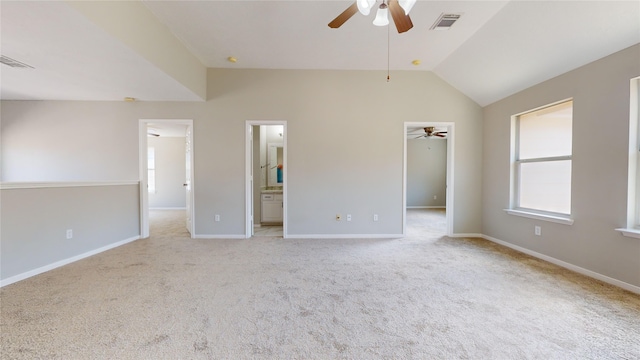 unfurnished bedroom with lofted ceiling, ceiling fan, connected bathroom, a walk in closet, and light colored carpet