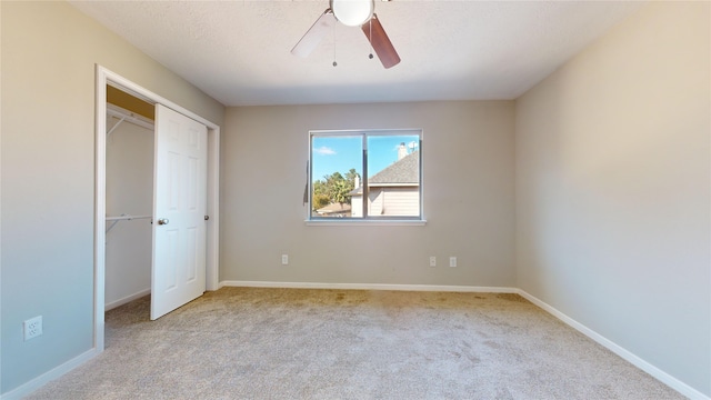 unfurnished bedroom with a closet, a textured ceiling, light colored carpet, and ceiling fan