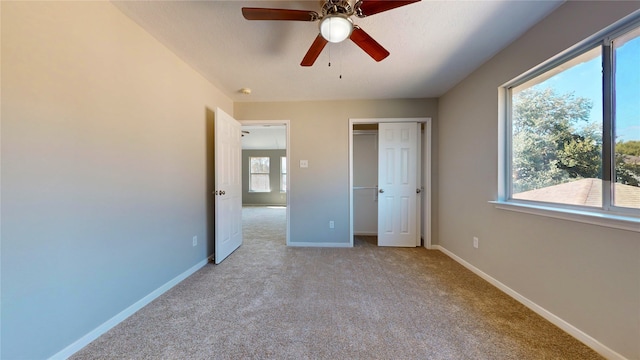 unfurnished bedroom featuring light carpet, multiple windows, and ceiling fan