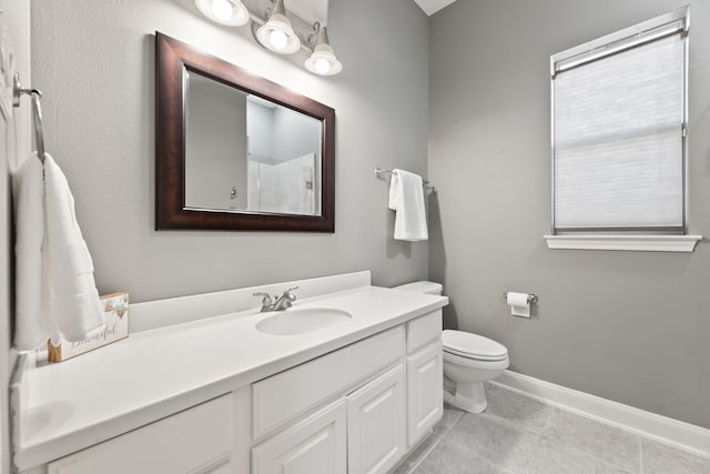 bathroom with toilet, vanity, and tile patterned flooring