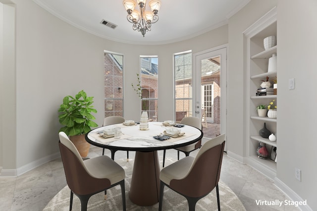 dining room with crown molding, built in features, and an inviting chandelier