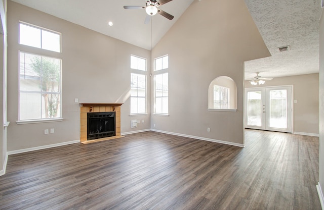 unfurnished living room featuring a healthy amount of sunlight, high vaulted ceiling, and dark wood-type flooring